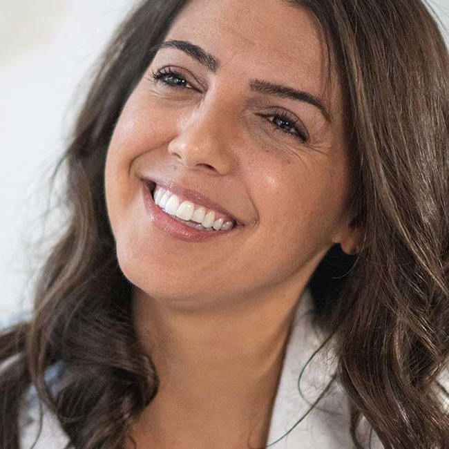 En kvindelig behandler sidder smilende og kigger på en patient.