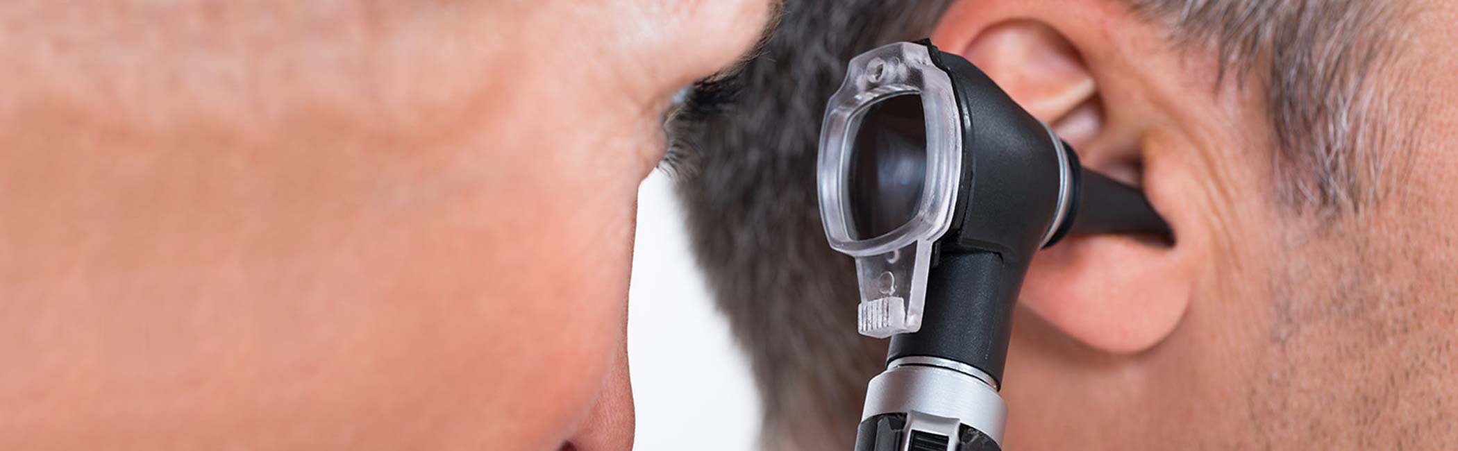 Læge kigger ind i øret på en patient med et otoskop