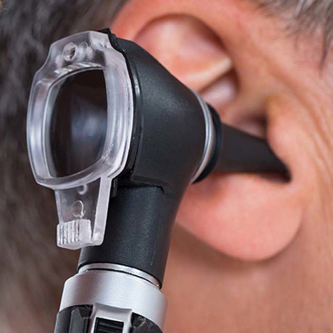 Læge kigger ind i øret på en patient med et otoskop