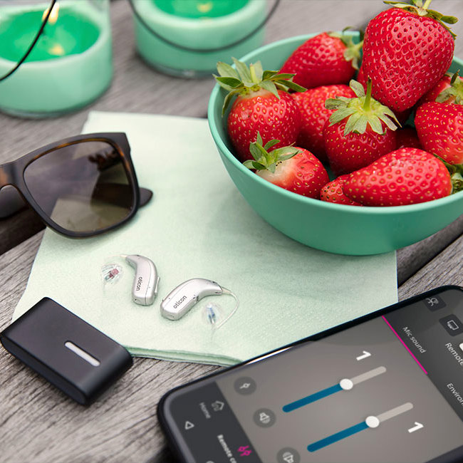 Oticon miniRITE høreapparat ligger på bord sammen med en ConnectClip og iPhone