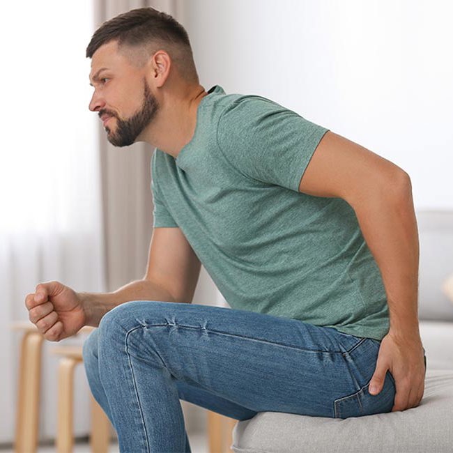 Mand sidder med smerter i endetarmen inden hæmoridebehandling.