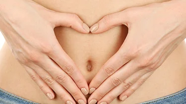 Kvinde laver et hjerte med sine hænder og holder det rundt om sin nygravide mave.