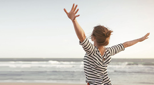 En kvinde laver yoga på stranden ved solnedgang.