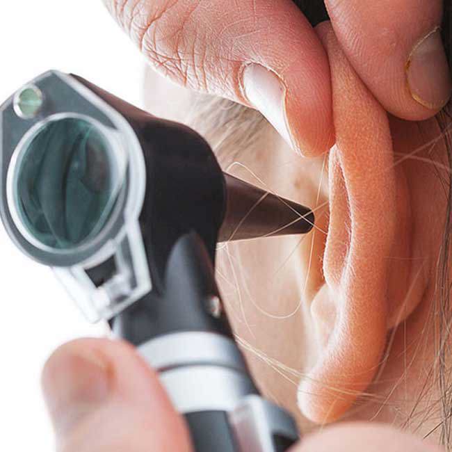 Læge tjekker patient efter hul på trommehinden.