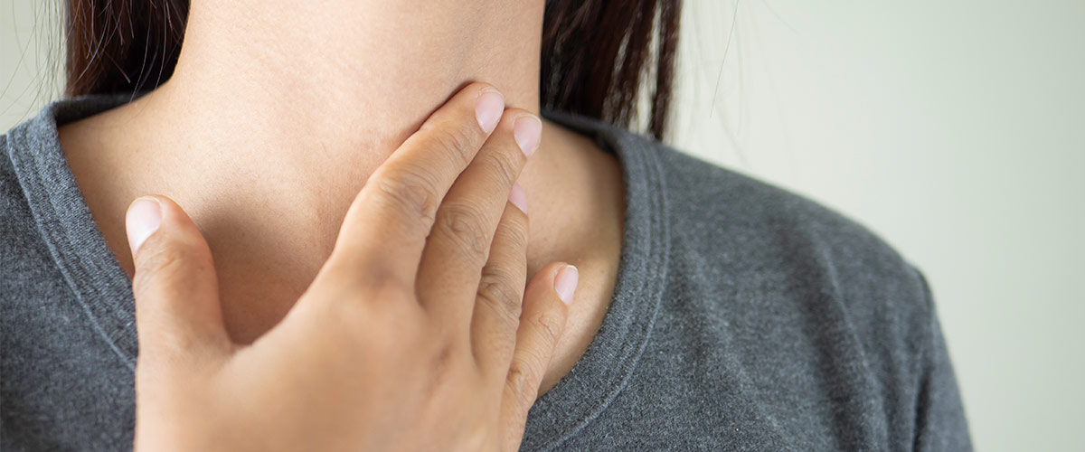 En kvinde tager sig til halsen.