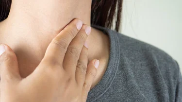 En kvinde tager sig til halsen.