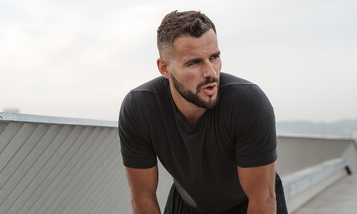 Mand står stille let foroverbøjet og prøver at få vejret.