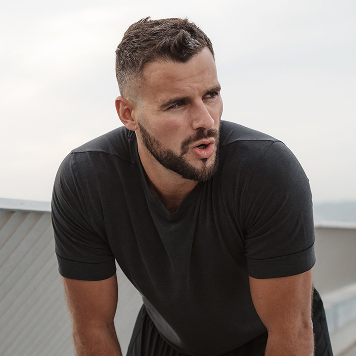 Mand står stille let foroverbøjet og prøver at få vejret.