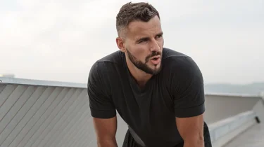 Mand står stille let foroverbøjet og prøver at få vejret.