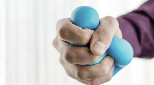 Patient øver øvelser fra ergoterapeut med massebold i hånden.