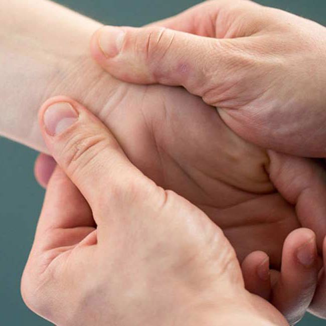 En kvinde masseres i hånden.