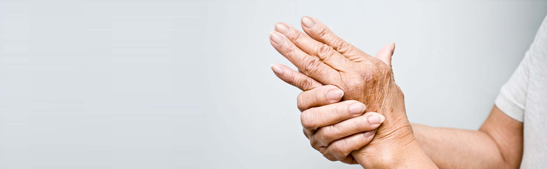 Ældre kvinde strækker sine hænder grundet håndsmerter.