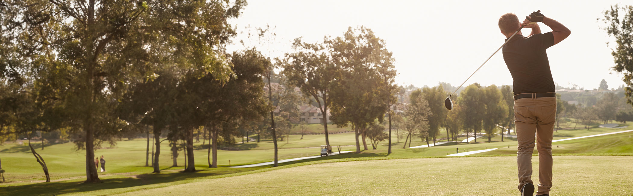 Mand slår en golfbold ud fra tee.