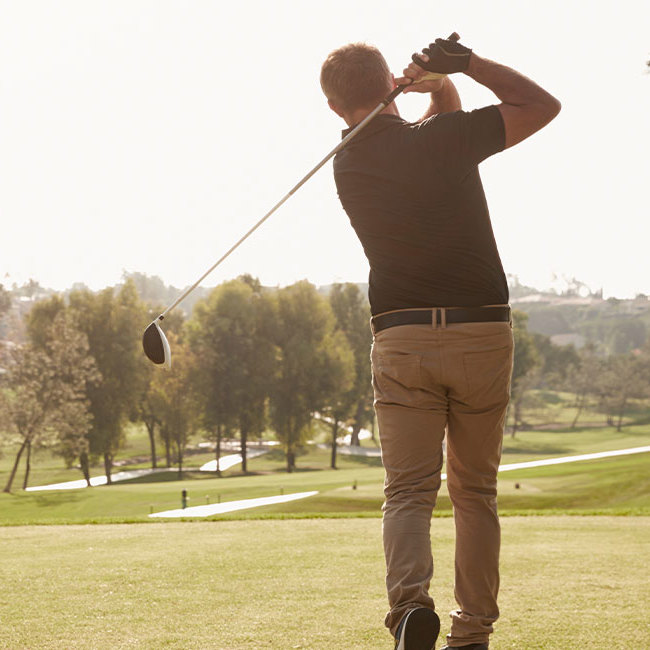 Mand slår en golfbold ud fra tee.