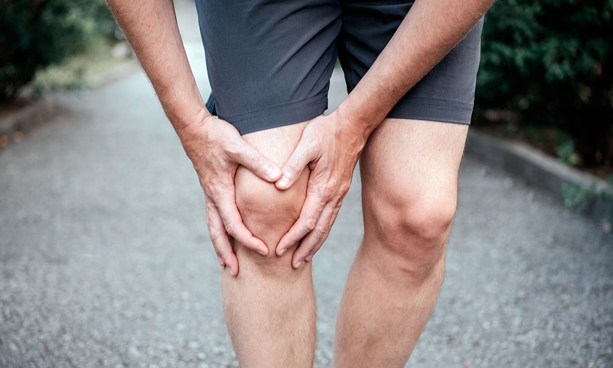 Mand holder sig til knæ, der gør ondt.