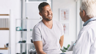 En patient og ortopædkirurg smiler under konsultation.