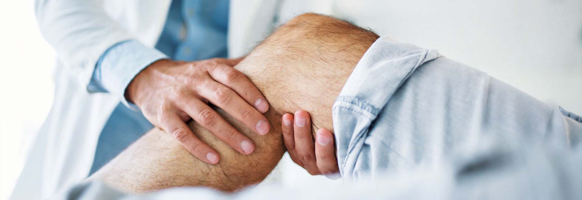 Ortopædkirurg mærker patient om knæet.