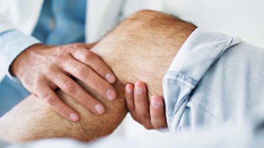 Ortopædkirurg mærker patient om knæet.