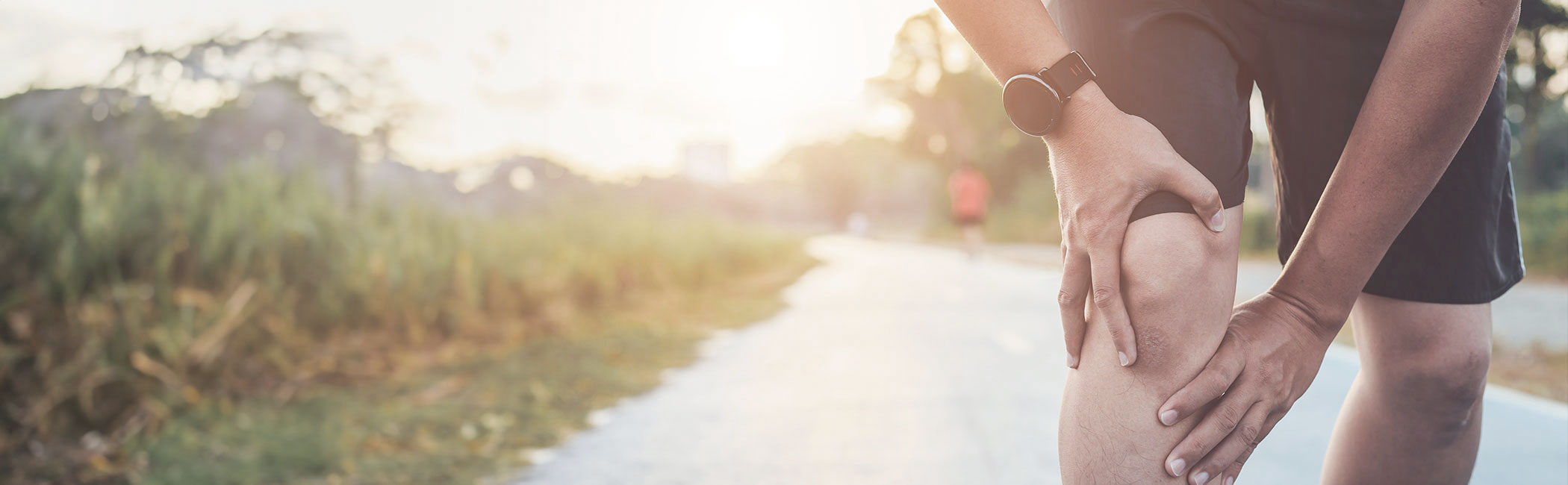 Mand har fået ondt i knæet på sin løbetur og er stoppet op for at undersøge knøet.