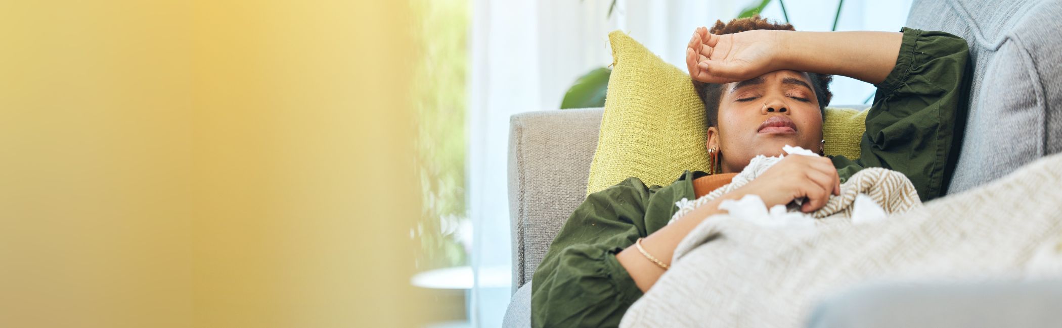 Kvinde ligger i sin sofa og er syg.