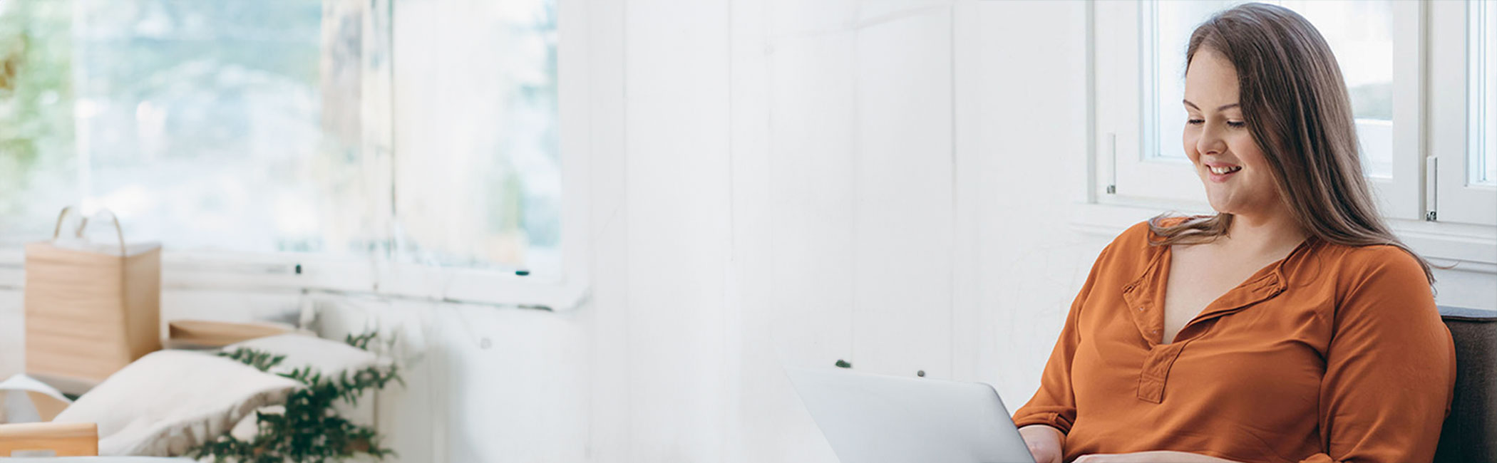 Smilende ung kvinde sidder ved sin computer og er ved af booke tid til en overvægtsoperation.