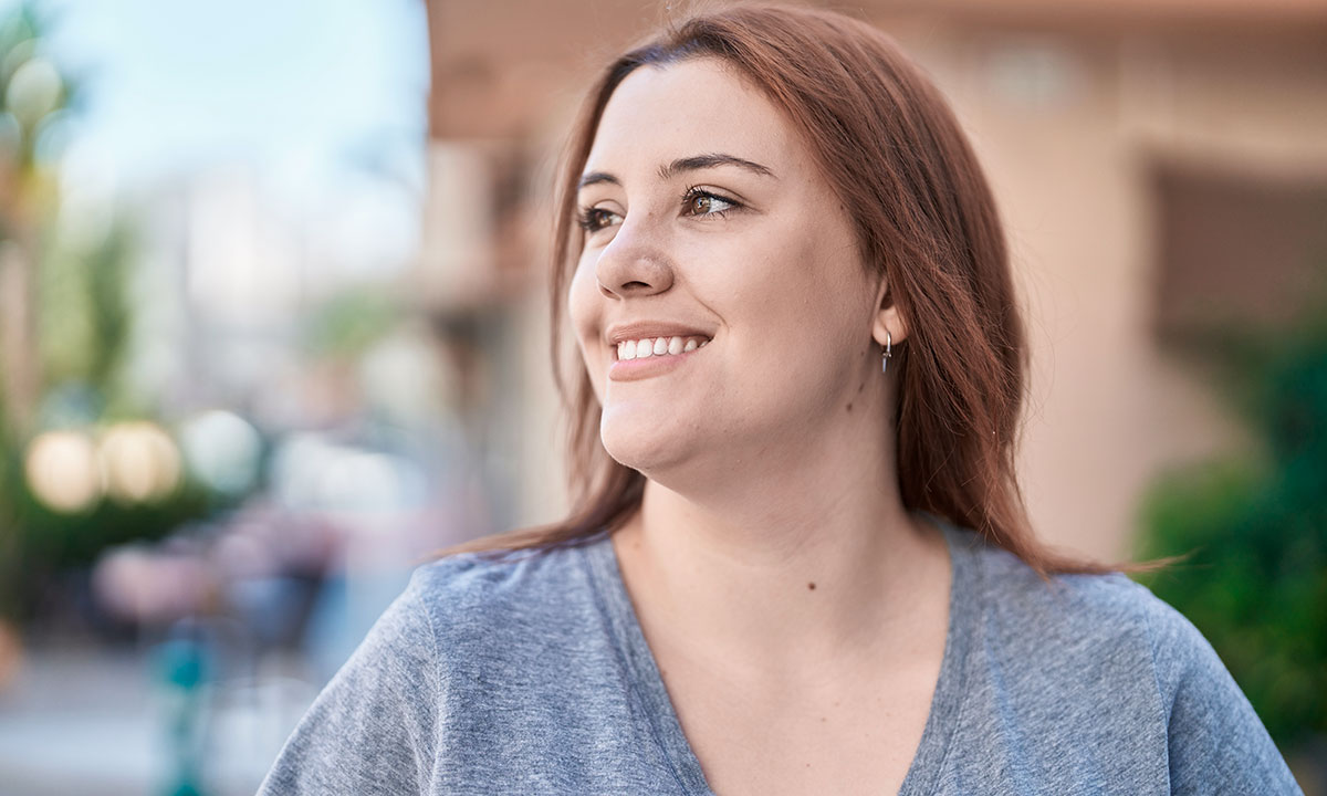 Ung smilende kvinde kommer gående på gaden.