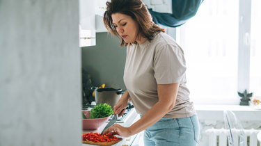Kvinde står og forbereder mad i køkken efter råd fra en diætist.