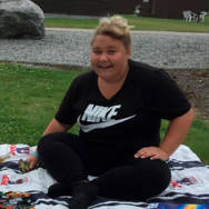 Frederikke på et tæppe i en park smiler til fotografen i perioden før hendes overvægtsoperation