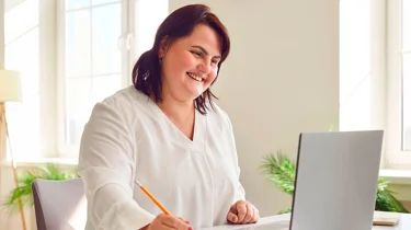 En glad kvinde smiler, fordi hun er blevet henvist til en overvægtsoperation på Aleris.