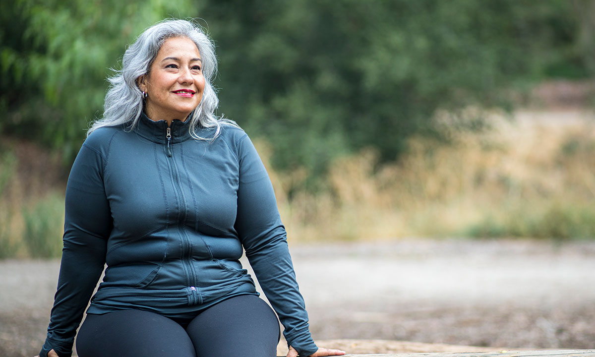 Glad kvinde går i naturen efter et vægttab hos Aleris.