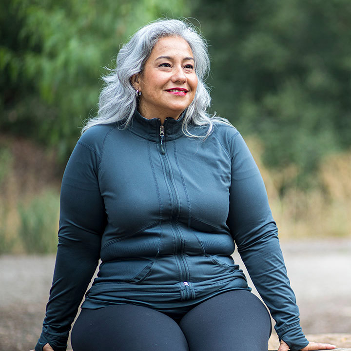 Glad kvinde går i naturen efter et vægttab hos Aleris.