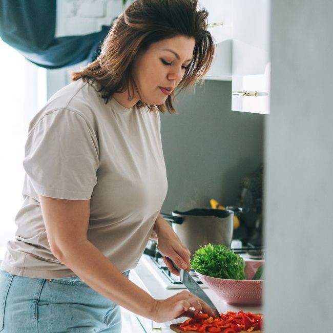 Kvinde laver mad i sit køkken efter råd fra diætist.