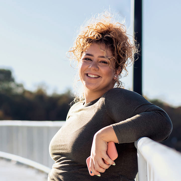 Kvinde står på en bro og smiler efter, at hun har motioneret.