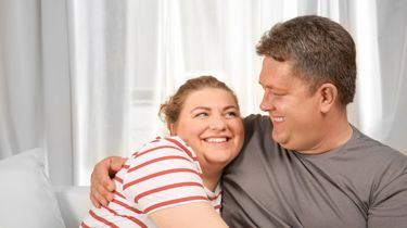 Et glad par krammer i sofaen.