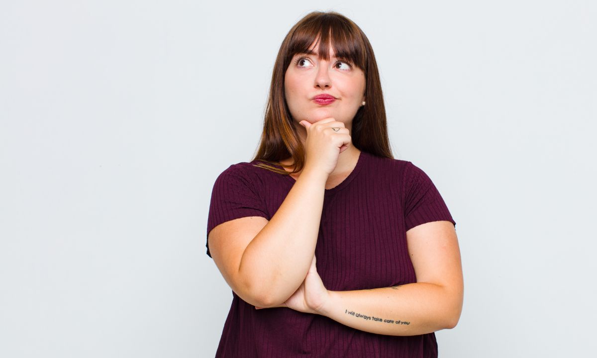 Overvægtig kvinde står og tænker.