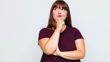 Overvægtig kvinde står og tænker.