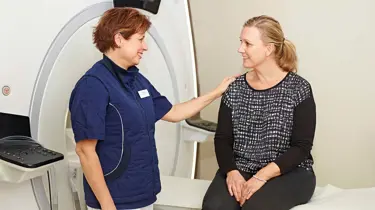 Læge og patient smiler ved en magnetkamera.