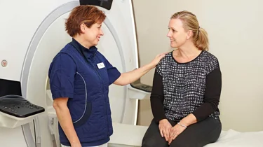 Læge og patient smiler ved en magnetkamera.