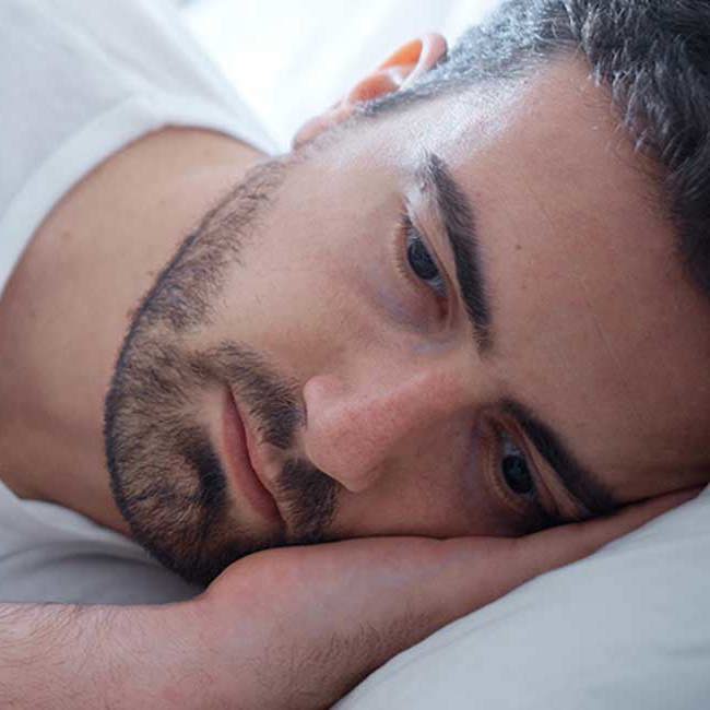 Mand ligger søvnløs i sin seng.