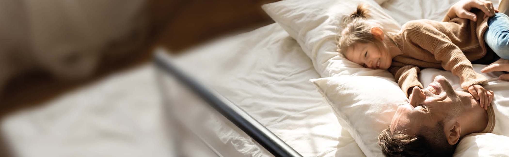 Far og datter ligger i sengen og griner.