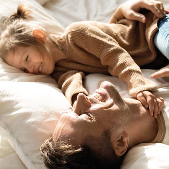 Far og datter ligger i sengen og griner.