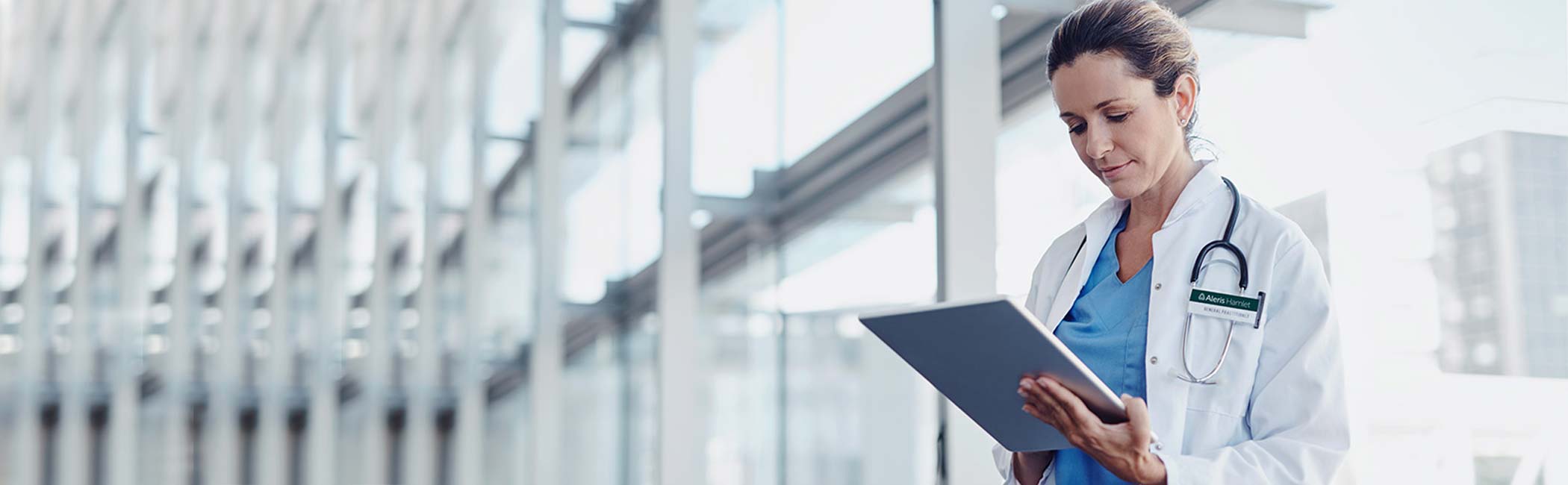 Læge står og kigger ned på en skærm.