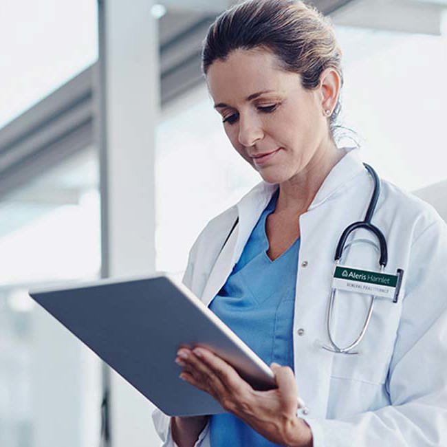 Læge står og kigger ned på en skærm.