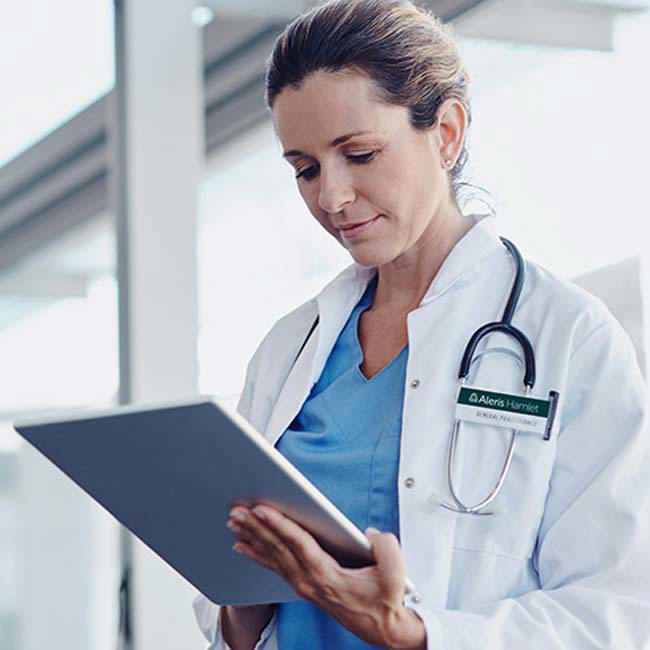 Læge står og kigger ned på en skærm.