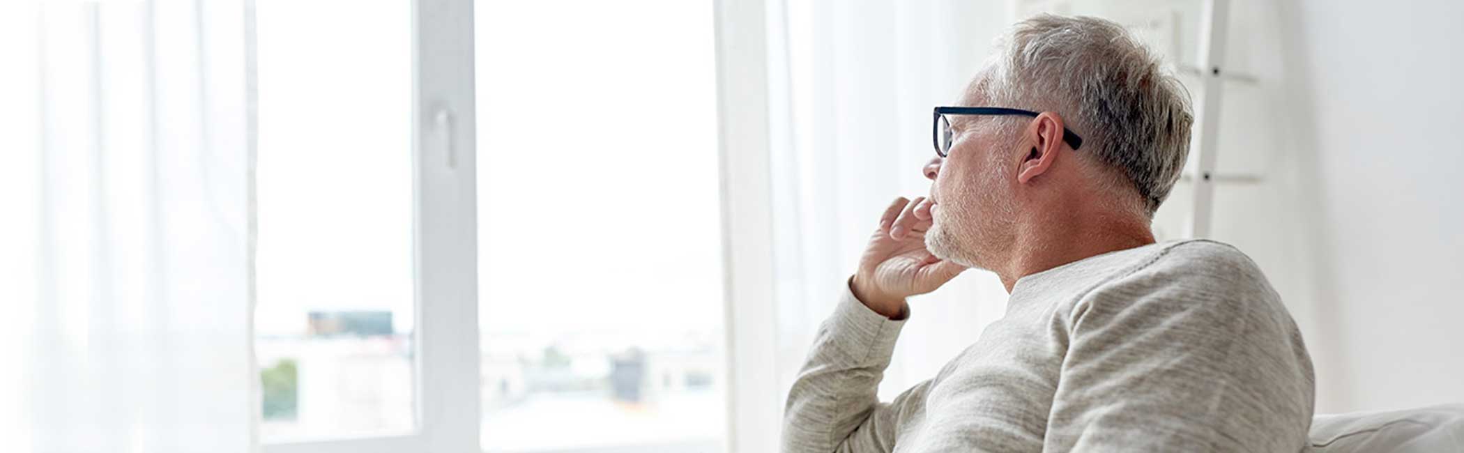 En mand kigger eftertænksomt ud af vinduet.