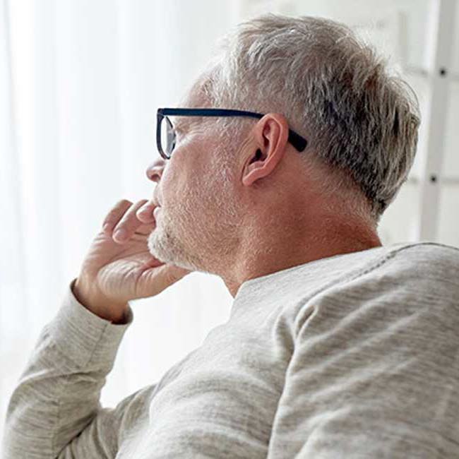 En mand kigger eftertænksomt ud af vinduet.