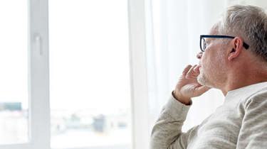 En mand kigger eftertænksomt ud af vinduet.