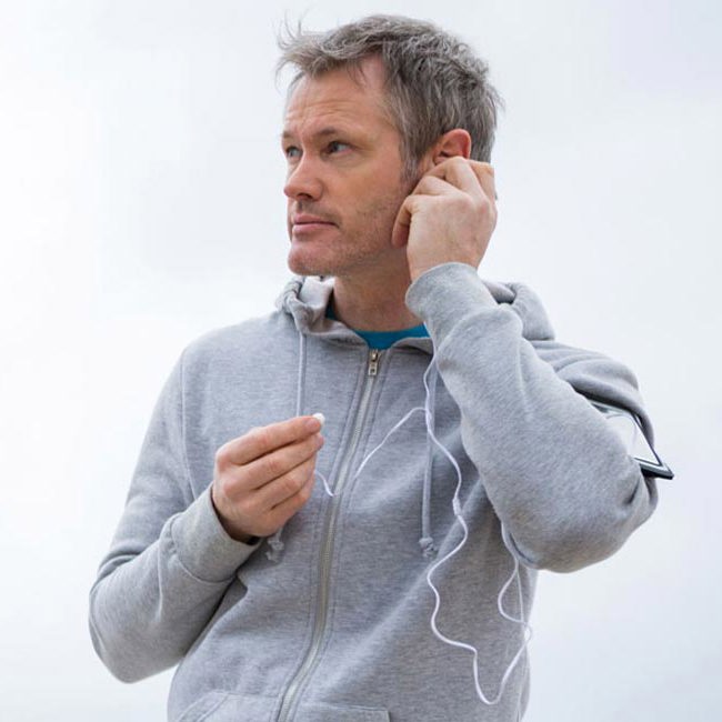 En mand går i naturen og lytter til musik.