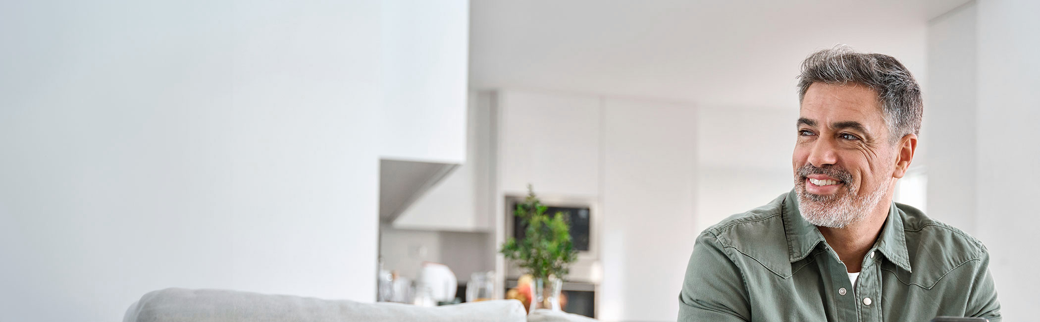 Mand 50+ sidder i sofa og smiler.