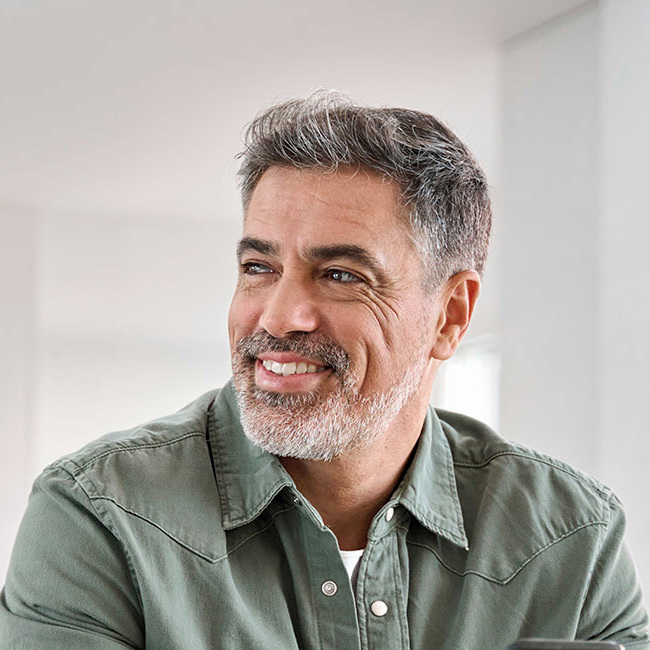 Mand 50+ sidder i sofa og smiler.